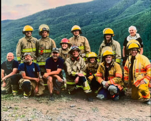 firefighting crew poses in front of forested hills
